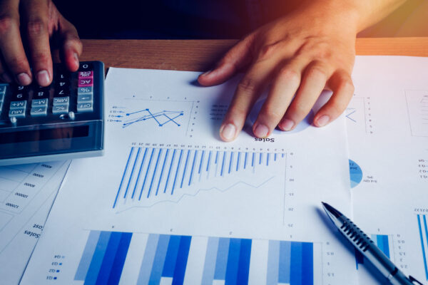 Selective focus hand asian business man is calculating finance and accounting with growth up paper chart on wood table in home office.Pen calculator graph document on desk.economy,saving,financial.